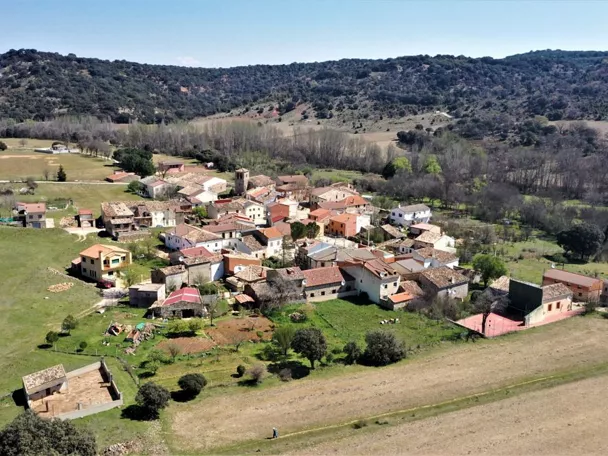 Vista aérea de un pequeño pueblo rodeado de praderas y colinas.