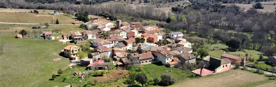 Vista aérea de un pequeño pueblo rodeado de praderas y colinas.