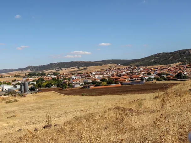 Vista panorámica de un pueblo con campos y colinas alrededor.