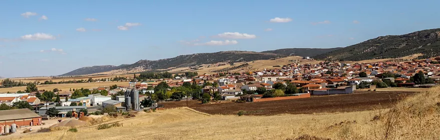 Vista panorámica de un pueblo con campos y colinas alrededor.
