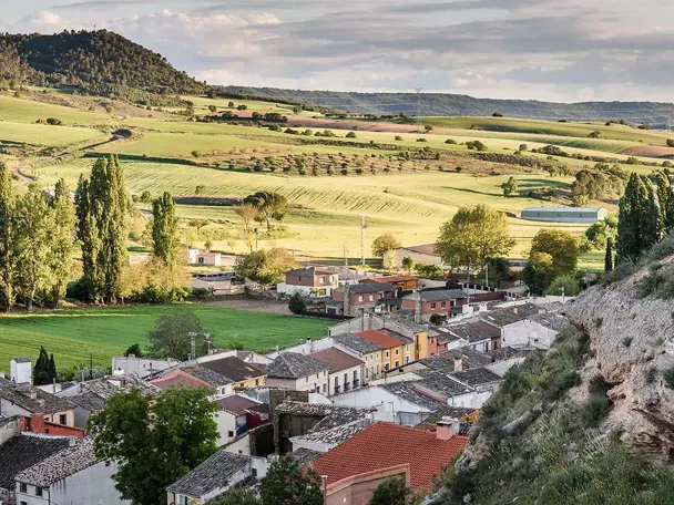 Vista panorámica de un pueblo rodeado de campos verdes y colinas.