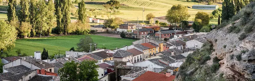 Vista panorámica de un pueblo rodeado de campos verdes y colinas.