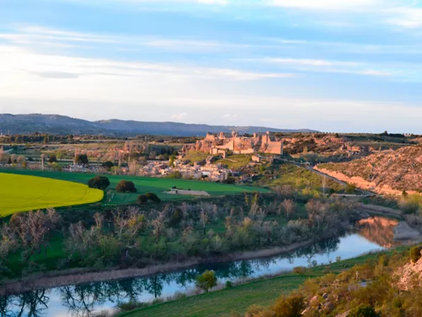 Vista panorámica de valle con río, campos verdes y conjunto histórico en lo alto