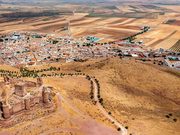 Vista aérea de pueblo rodeado de campos de cultivo y fortaleza en primer plano