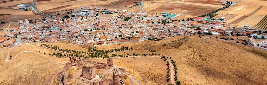 Vista aérea de pueblo rodeado de campos de cultivo y fortaleza en primer plano