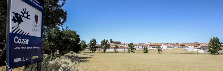 Entrada a Cózar con campos y pueblo al fondo.