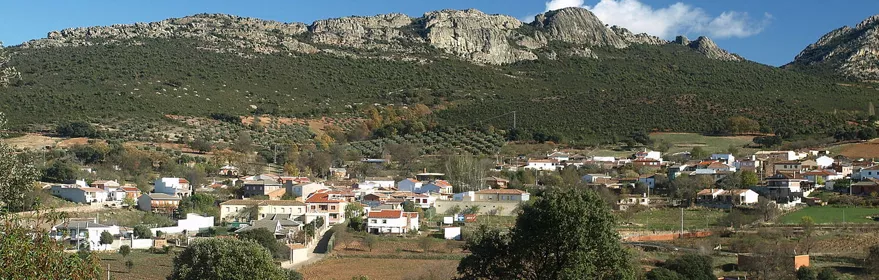 Vista panorámica del pueblo con casas blancas y sierra rocosa al fondo