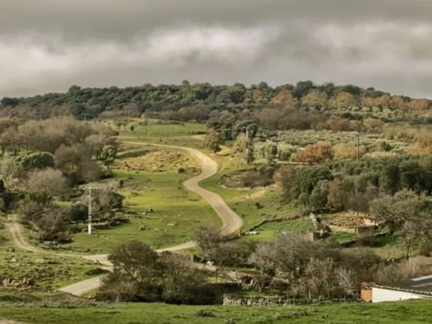 Paisaje rural con caminos y colinas verdes bajo cielo nublado
