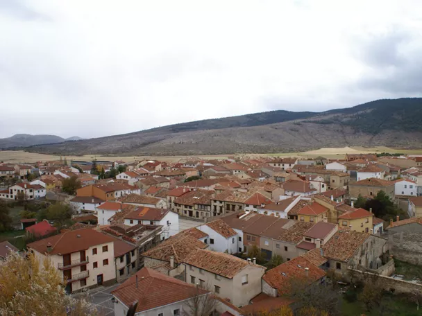 Vista panorámica de un pueblo con tejados de teja roja rodeado de colinas.