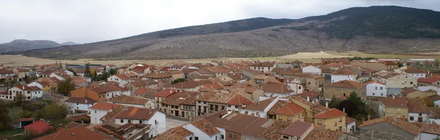 Vista panorámica de un pueblo con tejados de teja roja rodeado de colinas.