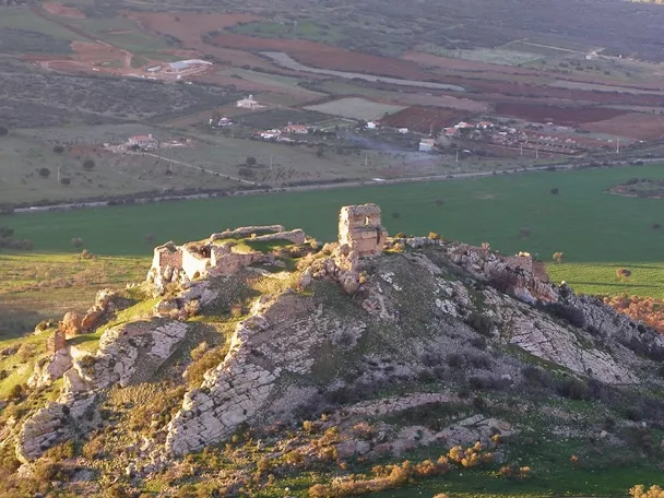 Ruinas de fortaleza sobre colina rodeada de campos