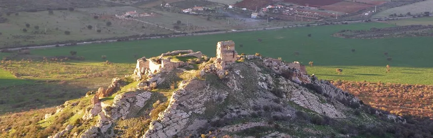 Ruinas de fortaleza sobre colina rodeada de campos