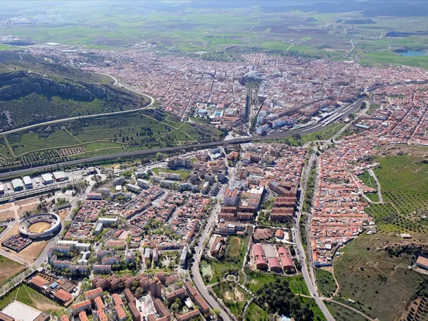 Vista aérea de una ciudad rodeada de zonas verdes y áreas residenciales.