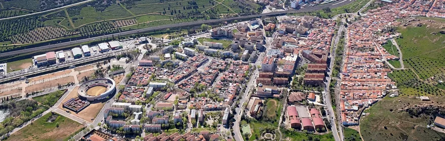 Vista aérea de una ciudad rodeada de zonas verdes y áreas residenciales.