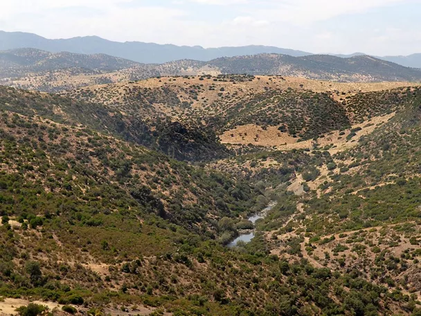 Valle con río entre colinas cubiertas de matorral