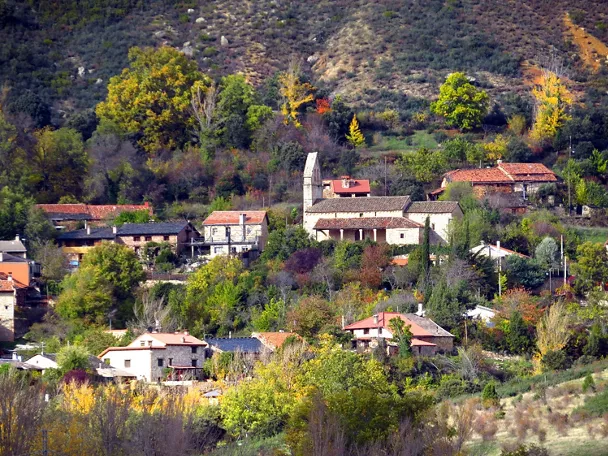 Vista panorámica de un pueblo entre colinas y vegetación otoñal.