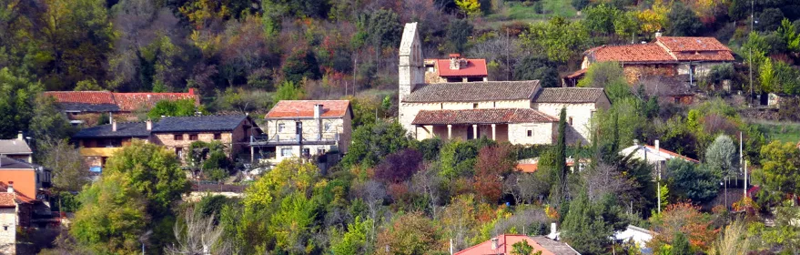 Vista panorámica de un pueblo entre colinas y vegetación otoñal.