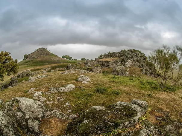 Afloramientos rocosos y colinas suaves con vegetación bajo cielo cubierto
