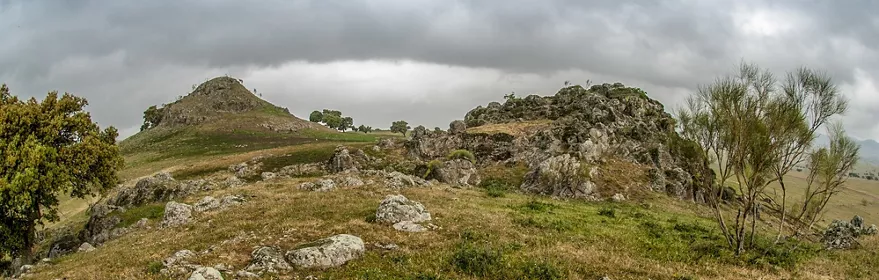 Afloramientos rocosos y colinas suaves con vegetación bajo cielo cubierto
