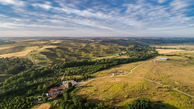 Panorámica de colinas verdes y campos abiertos con edificaciones dispersas.