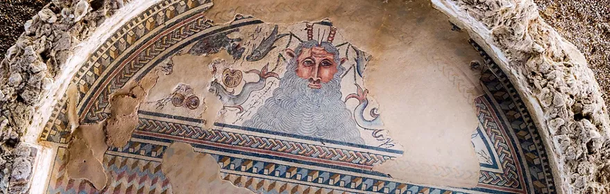 Detalle de mosaico antiguo con figura barbada rodeada de decoración geométrica.