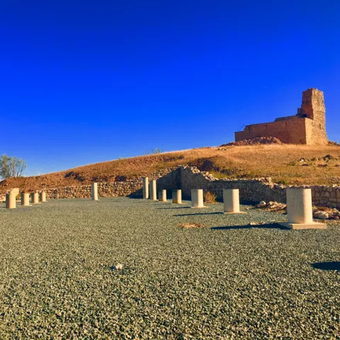 Vista del yacimiento arqueológico con castillo al fondo