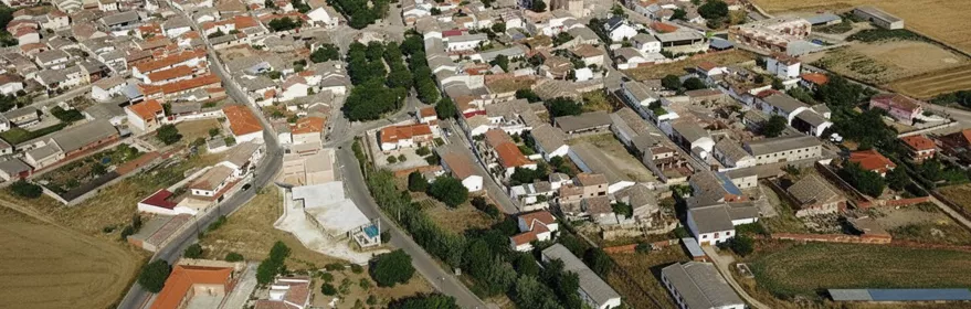 Una vista aérea captura un pequeño pueblo con casas de techos de color rojo-anaranjado y paredes blancas