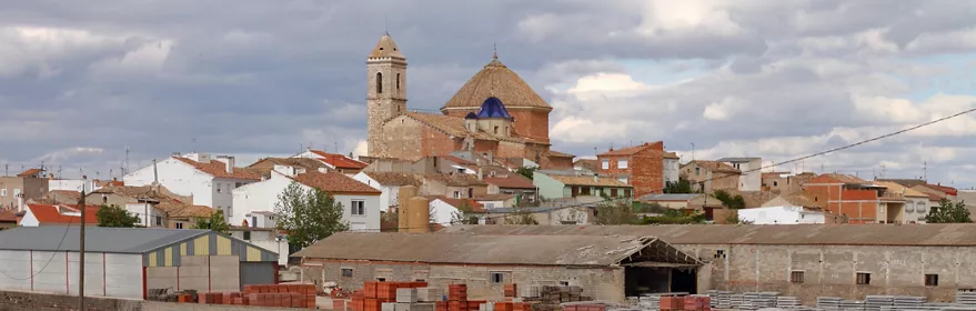 Vista panorámica de pueblo con iglesia, naves industriales y campos