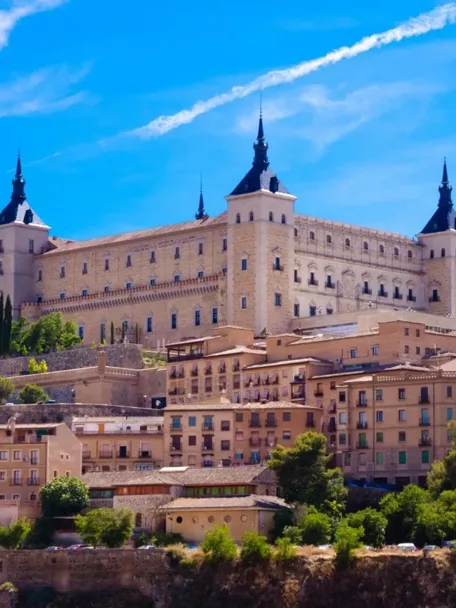 Conjunto monumental amurallado sobre una colina con casas tradicionales en primer plano.