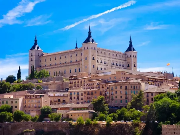 Conjunto monumental amurallado sobre una colina con casas tradicionales en primer plano.