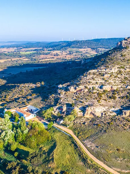 Paisaje rural con montaña rocosa y campos agrícolas.