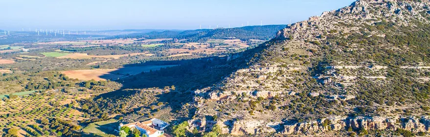 Paisaje rural con montaña rocosa y campos agrícolas.