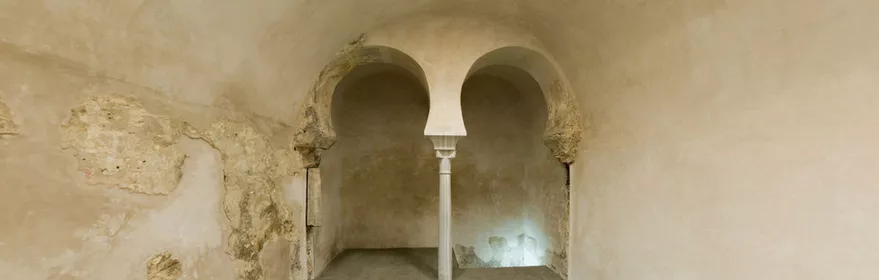 Estancia rectangular con doble arco de herradura y paredes de yeso desgastado.