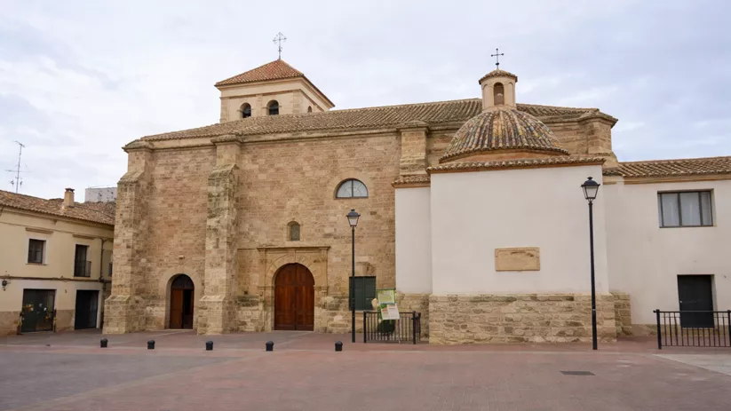 Iglesia de piedra junto a plaza amplia y farolas