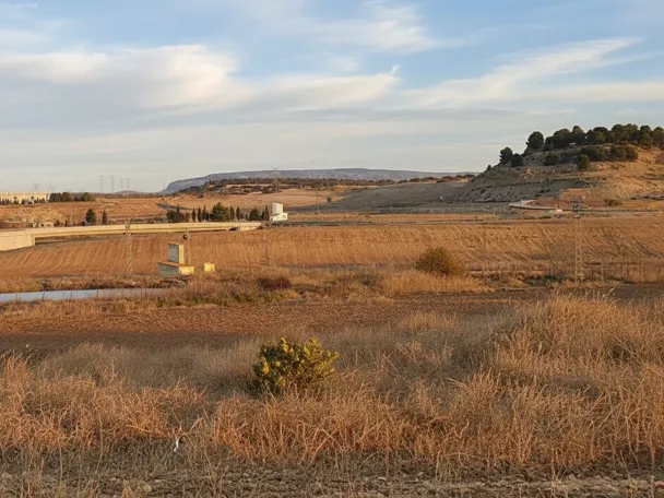Paisaje de campos secos con carretera, colinas y aerogeneradores