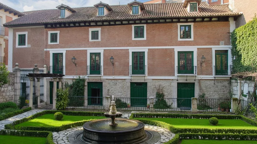 Jardín interior con fuente central y edificio de ladrillo al fondo.