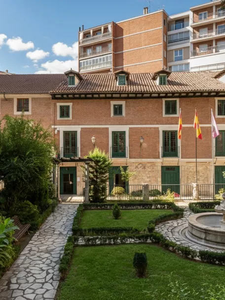 Jardín cuidado con senderos de piedra, fuente circular y edificio histórico al fondo.