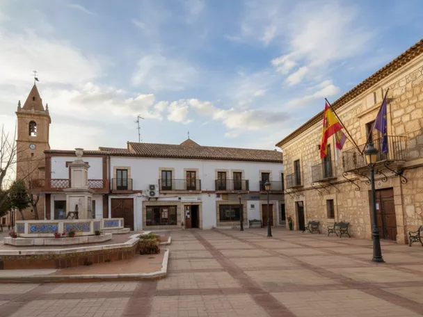 Plaza amplia con fuente, edificios públicos y torre de iglesia