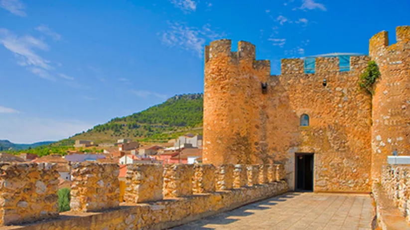 Acceso amurallado con paseo elevado y vistas al pueblo.