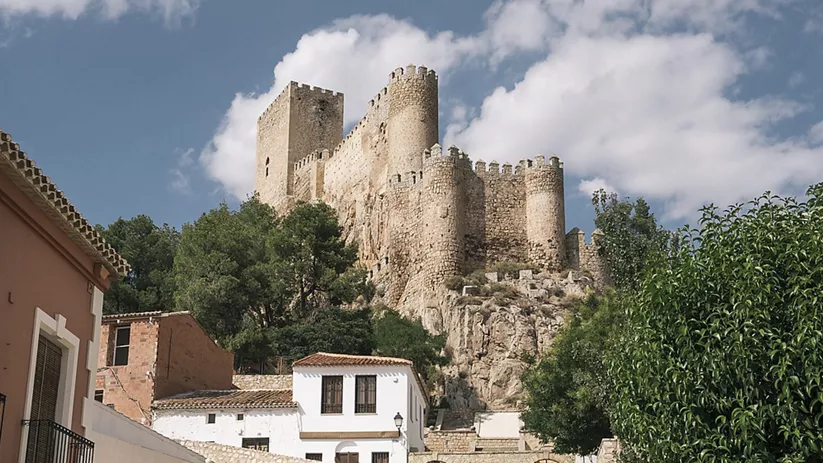 Castillo de piedra sobre una colina visto desde el pueblo