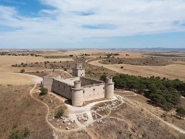 Vista aérea de fortaleza rodeada de llanuras y caminos rurales.