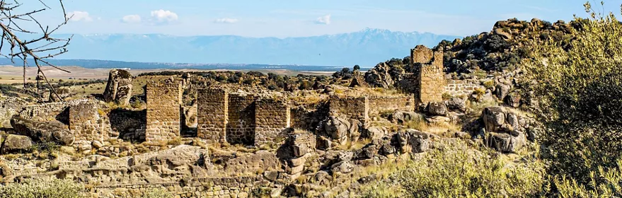 Ruinas de piedra entre rocas y llanura al fondo