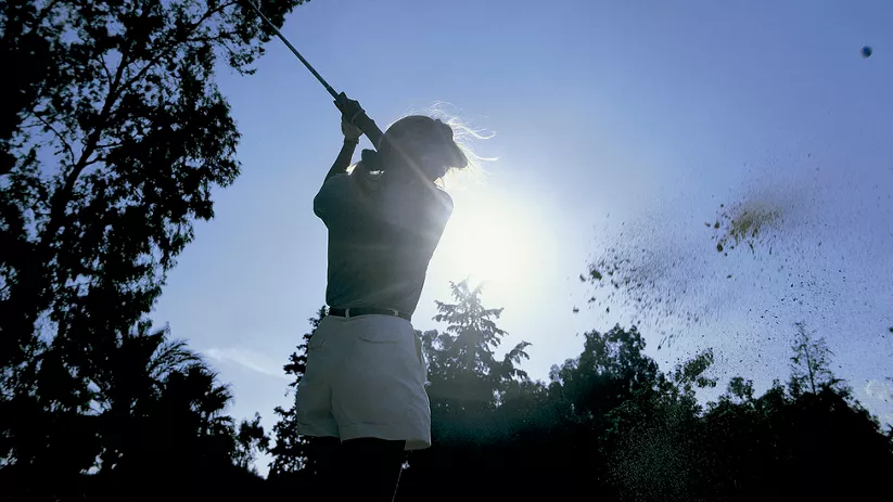 Imagen de una mujer golpeando la pelota de golf