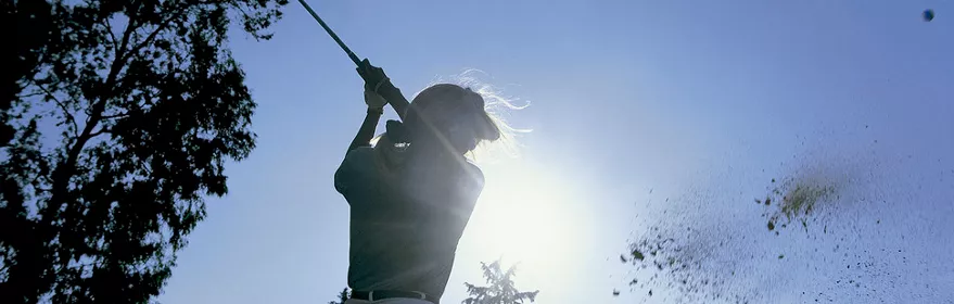 Imagen de una mujer golpeando la pelota de golf