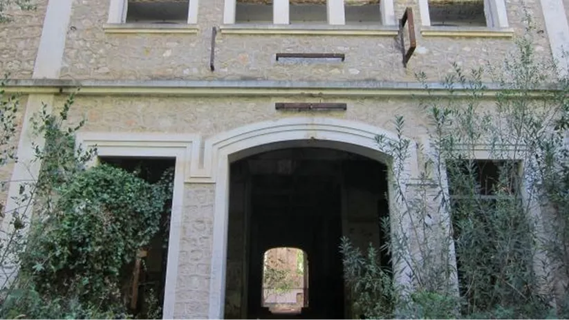 Fachada de construcción histórica deteriorada con ventanas abiertas.