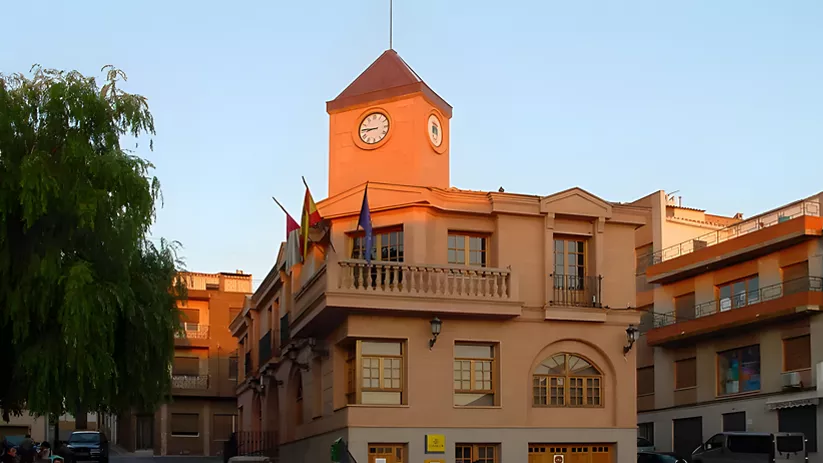 Fachada de ayuntamiento con reloj, balcones y banderas