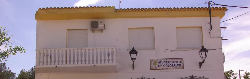 Fachada de edificio consistorial blanco con bancos y faroles