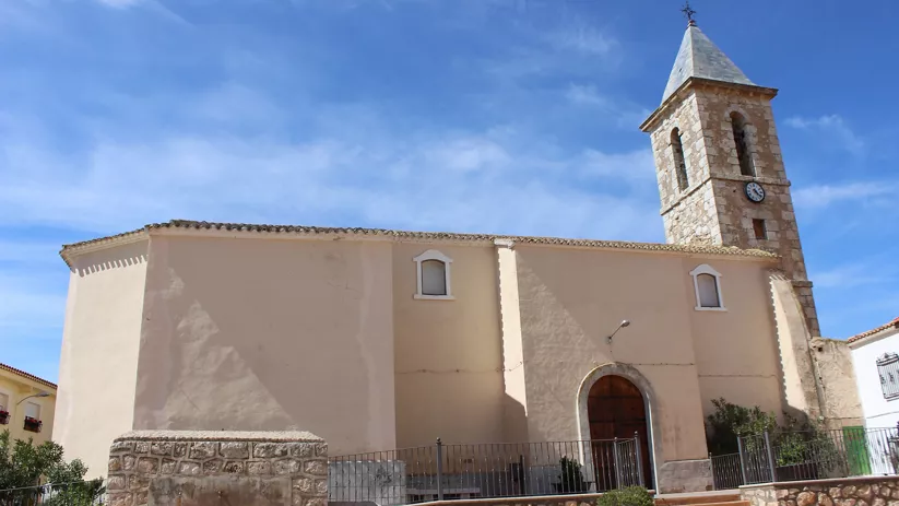 Iglesia de fachada clara con torre campanario y reloj