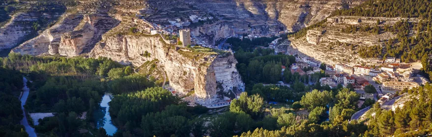 Vista aérea de un pueblo blanco encajado entre altos cortados rocosos y un río
