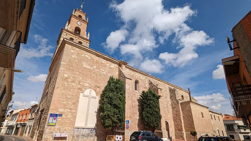 Iglesia de piedra en el casco urbano bajo cielo azul.